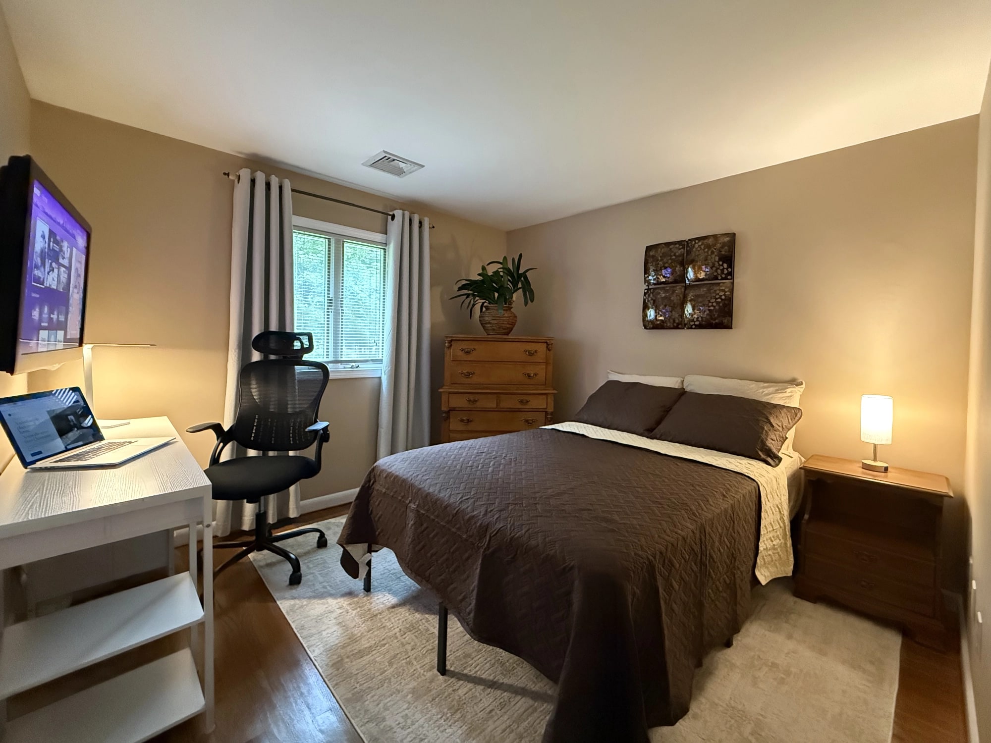 Furnished full room with bed, desk, ergonomic chair, dresser and window