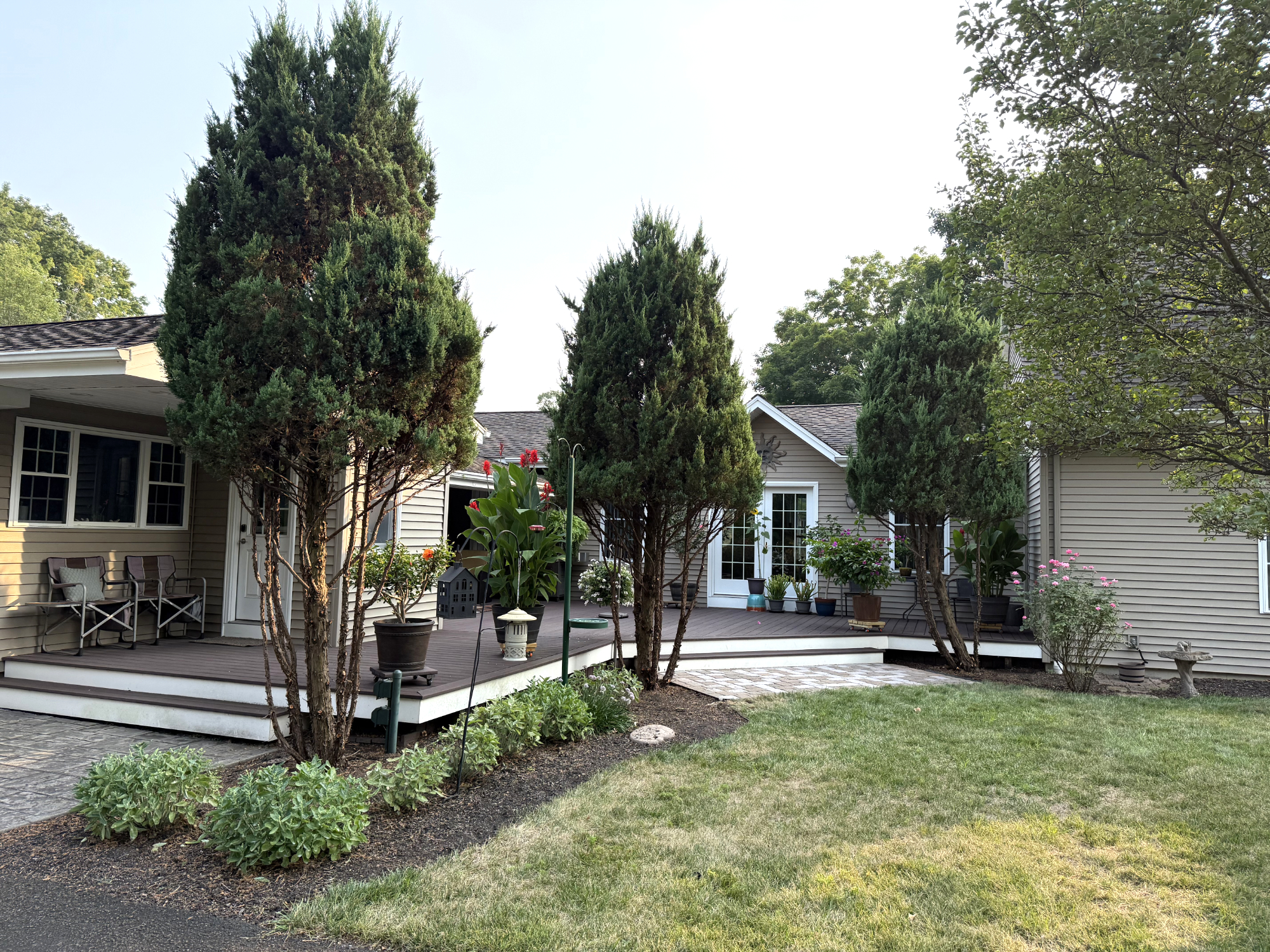 Large covered outdoor deck with seating and landscaped backyard views